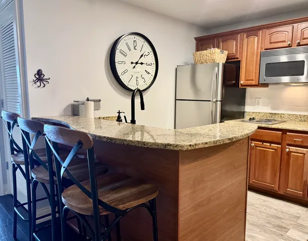a kitchen with granite countertop a table chairs stove and refrigerator