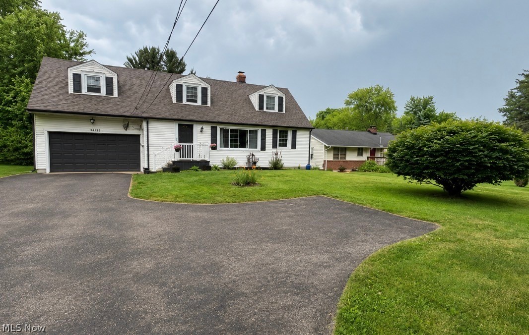 38155 Aurora Road Solon, OH 44139 - Photo 2 of 31 White siding residence featuring a dark asphalt shingle roof, black garage door, and a paved driveway
