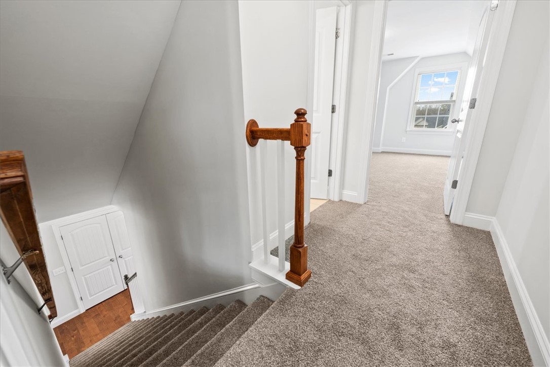 102 Ripplestone Way Anderson, SC 29621 - Photo 27 of 39 A view from the top of the carpeted stairs showcasing a bright hallway leading to a windowed room.