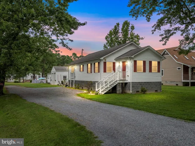 a view of a house next to a big yard with large trees