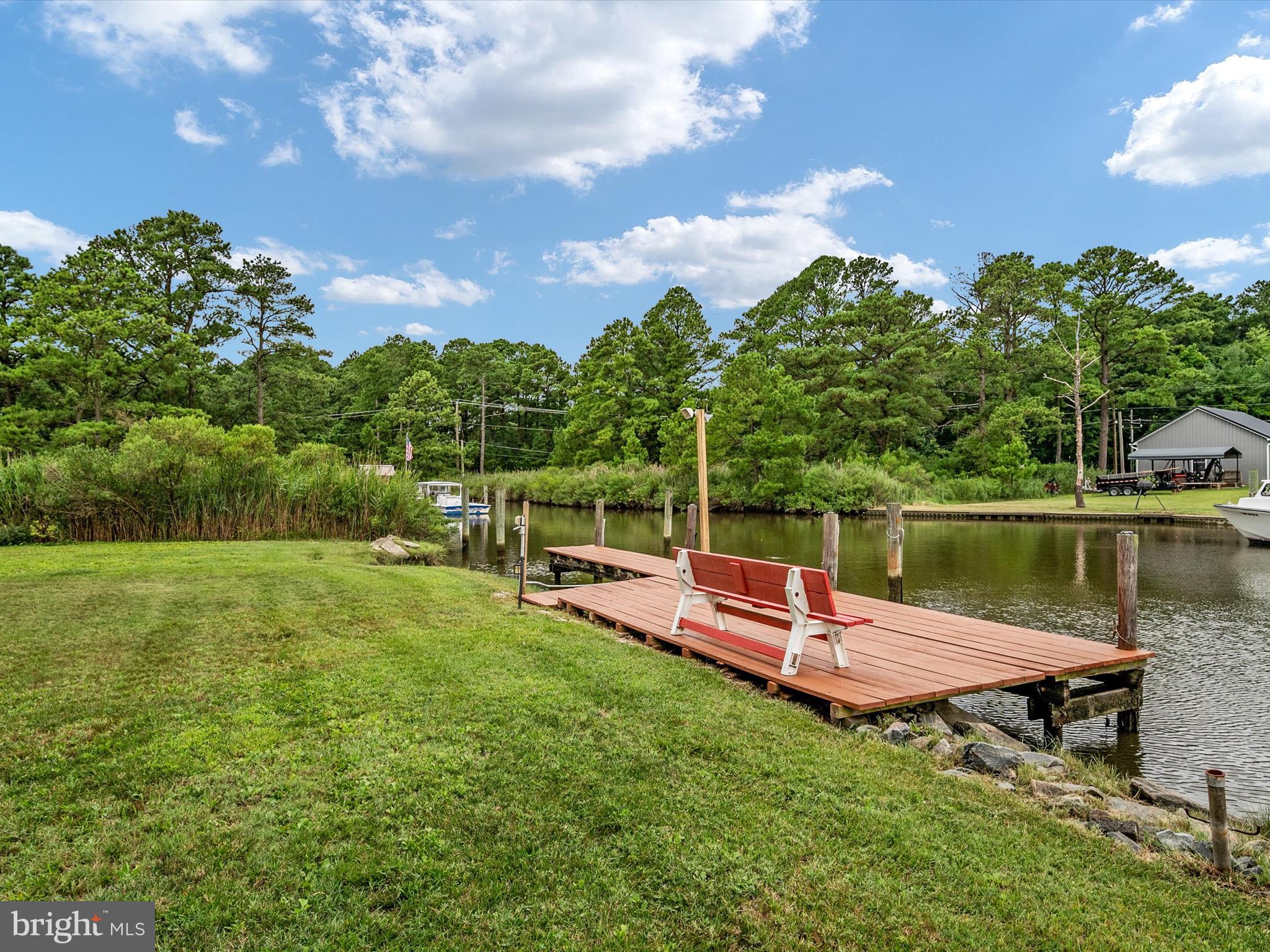 113 Radcliffe Road Grasonville, MD 21638 - Photo 25 of 30 a view of a lake with a bench and a wooden fence