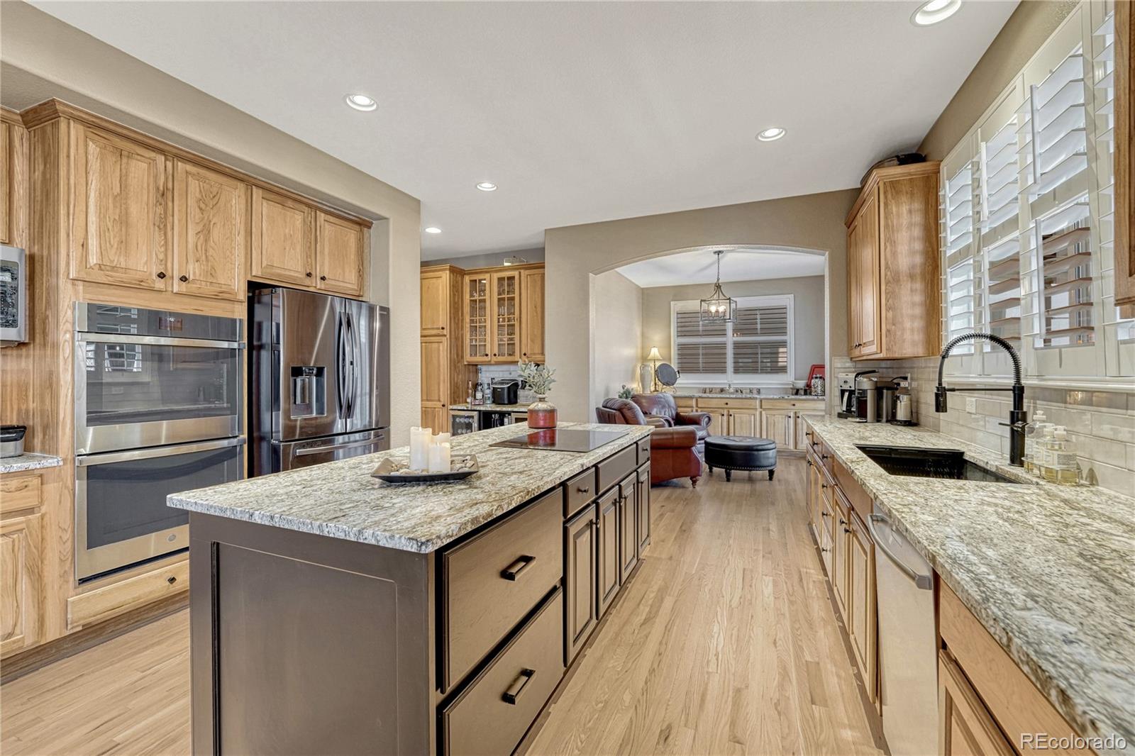 10761 Glengate Circle Highlands Ranch, CO 80130 - Photo 16 of 39 a kitchen with granite countertop kitchen island stainless steel appliances a sink stove and refrigerator