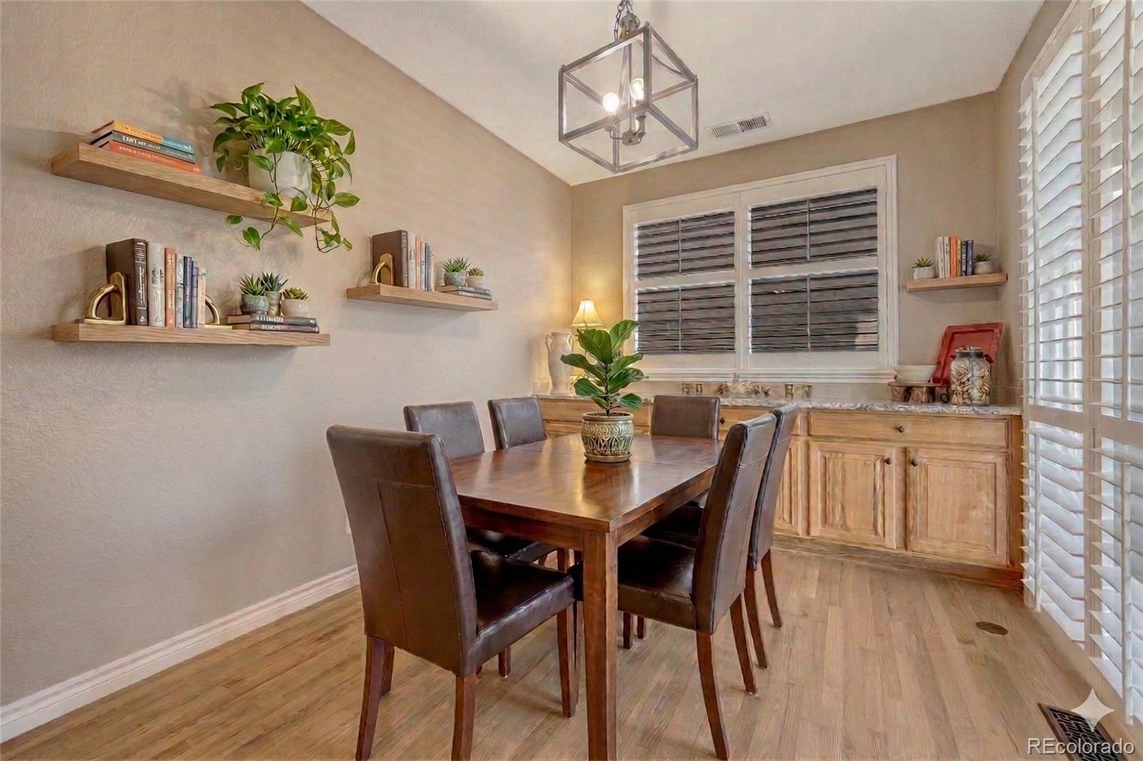10761 Glengate Circle Highlands Ranch, CO 80130 - Photo 18 of 39 a dining room with furniture potted plants and wooden floor