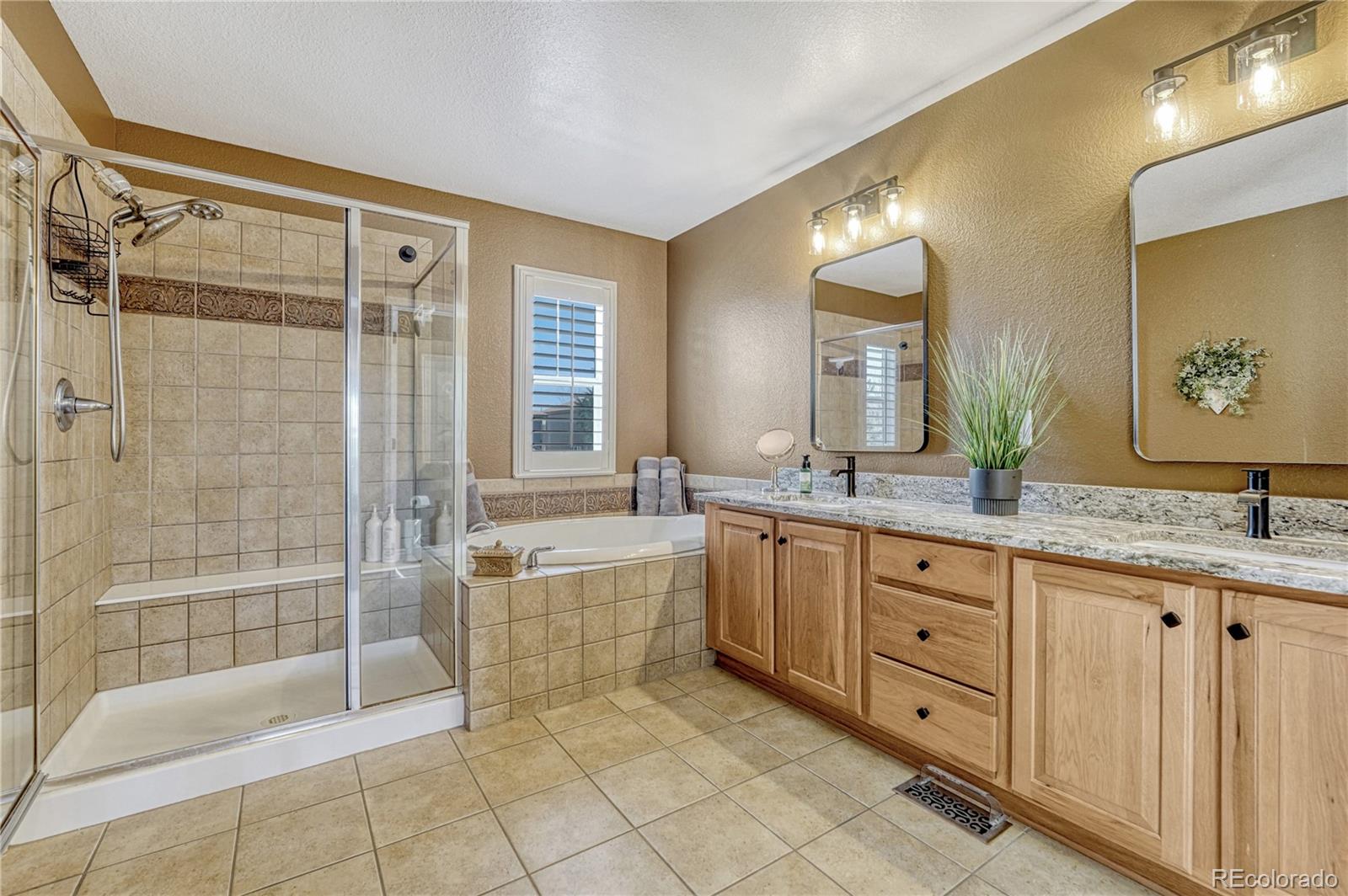 10761 Glengate Circle Highlands Ranch, CO 80130 - Photo 25 of 39 a bathroom with a granite countertop sink a large mirror and a bathtub