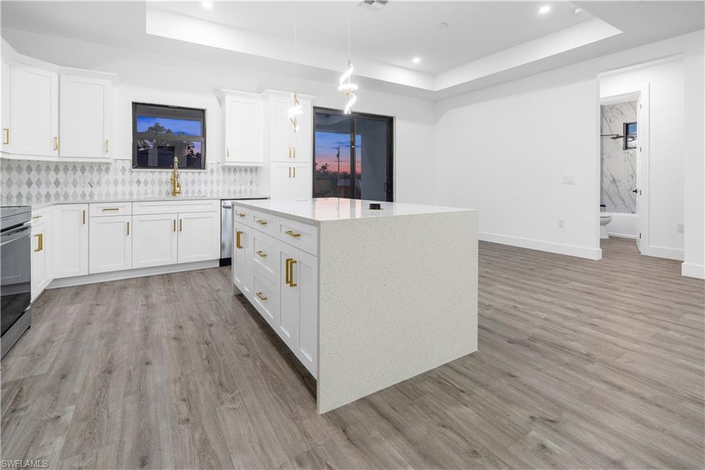 2714 24th Street West Lehigh Acres, FL 33971 - Photo 13 of 48 a large white kitchen with wooden floors and white cabinets