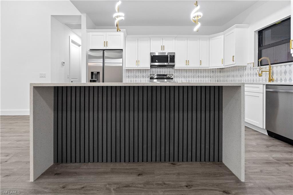 2714 24th Street West Lehigh Acres, FL 33971 - Photo 15 of 48 a kitchen with kitchen island granite countertop white cabinets a refrigerator and a sink