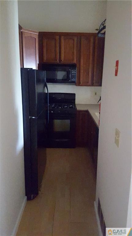 937 Edpas Road, Unit 937 New Brunswick, NJ 08901 - Photo 3 of 10 a kitchen with granite countertop wood cabinets and a refrigerator