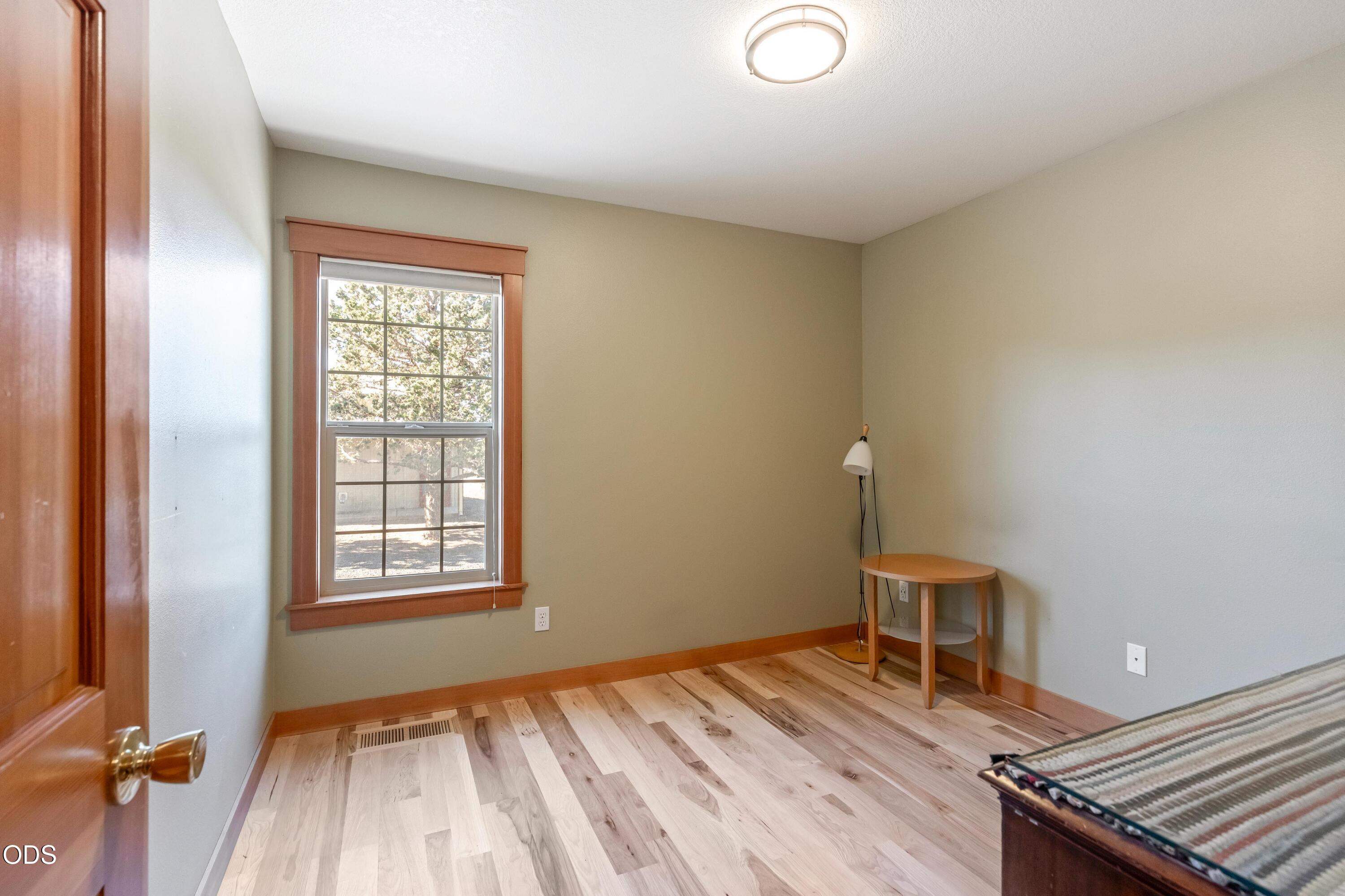 13753 South Sego Lily Road Powell Butte, OR 97753 - Photo 15 of 46 an empty room with wooden floor and windows