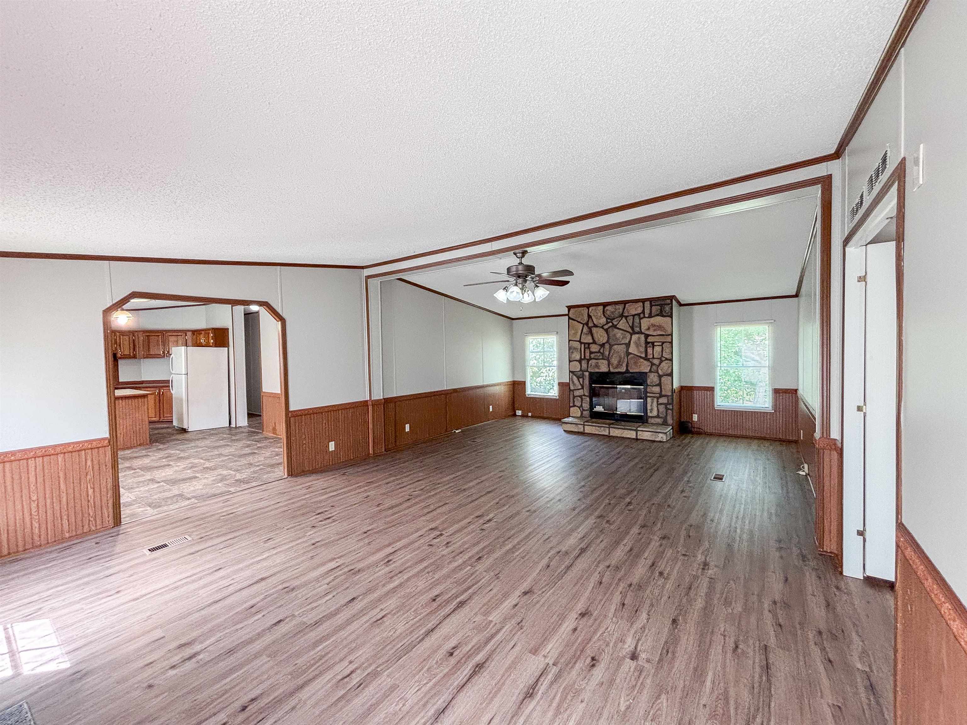 2847 Holly Grove Road Covington, TN 38019 - Photo 5 of 36 Spacious living area featuring wood-finish flooring, a stone fireplace, and a ceiling fan