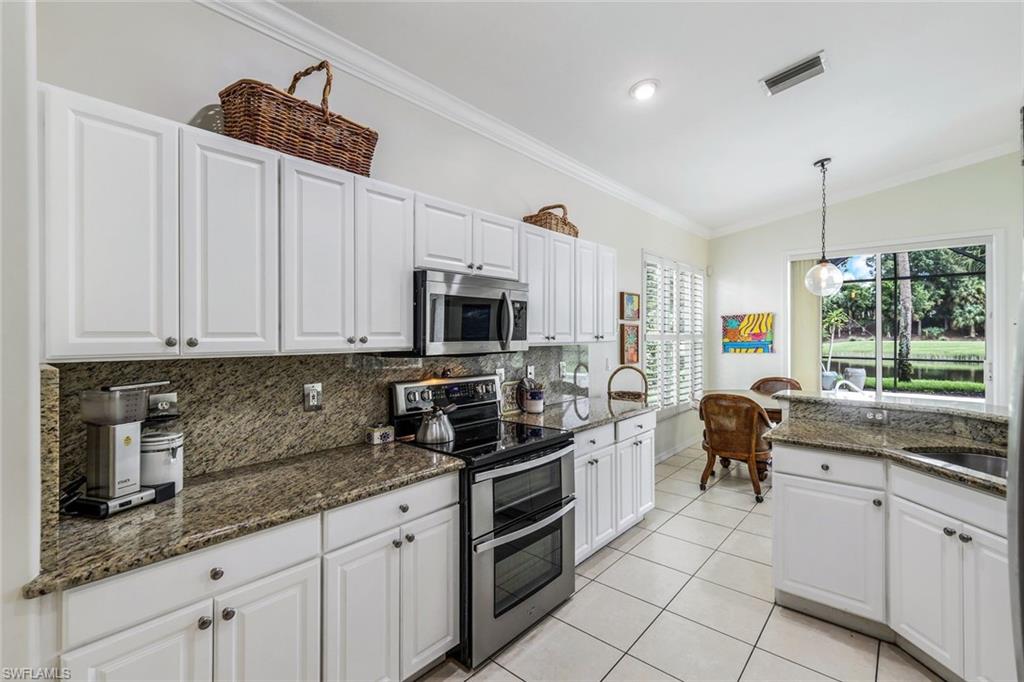 17983 Modena Road Miromar Lakes, FL 33913 - Photo 6 of 44 Kitchen featuring white cabinets, stainless steel appliances, decorative light fixtures, and dark stone counters