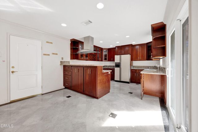 a room with stainless steel appliances kitchen island granite countertop a refrigerator and a stove top oven