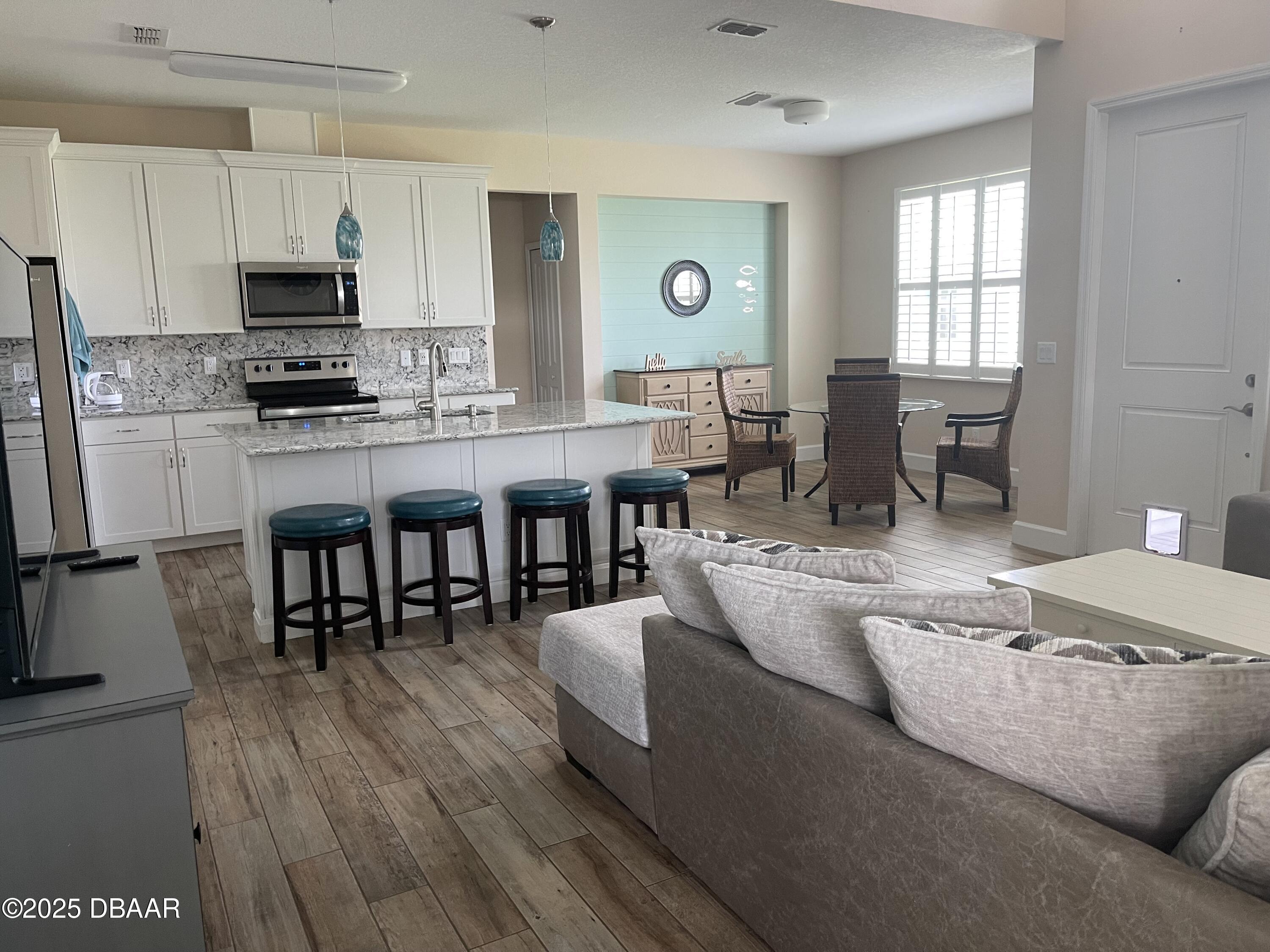 231 Ocean Hammock Loop Daytona Beach, FL 32124 - Photo 6 of 39 a living room with stainless steel appliances granite countertop furniture a fireplace a flat screen tv and a window