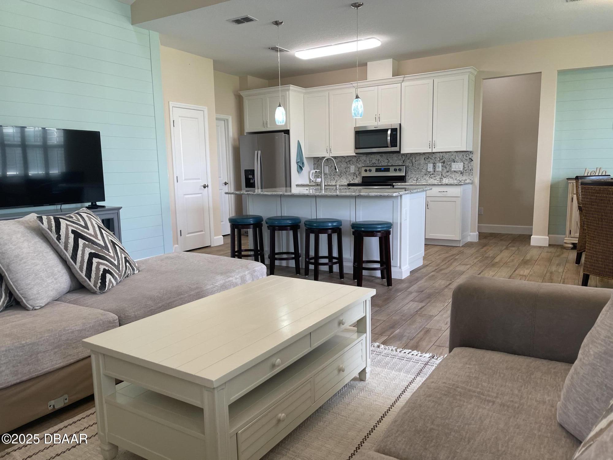 231 Ocean Hammock Loop Daytona Beach, FL 32124 - Photo 7 of 39 a living room with kitchen island furniture and a flat screen tv