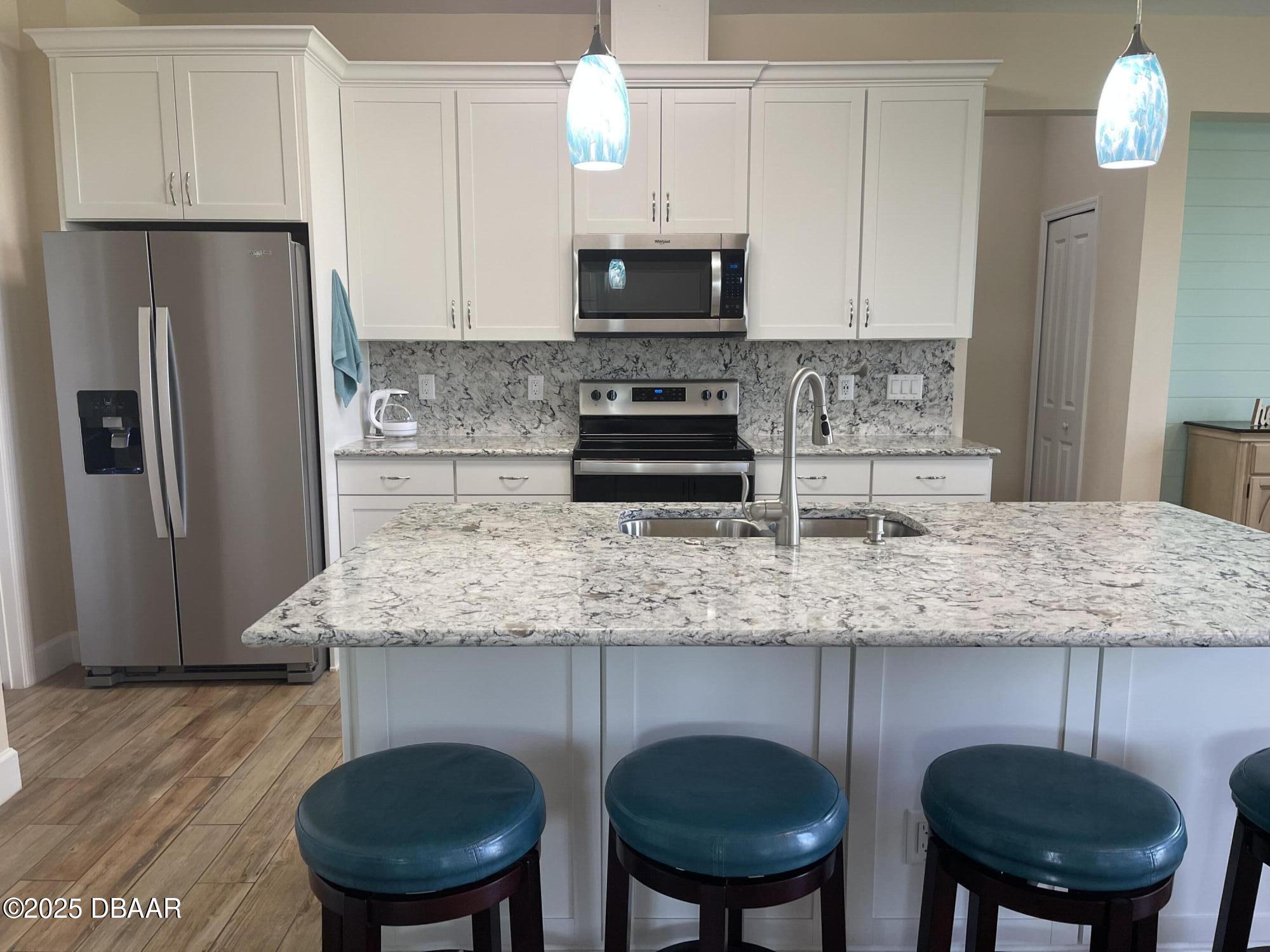 231 Ocean Hammock Loop Daytona Beach, FL 32124 - Photo 10 of 39 a kitchen with stainless steel appliances granite countertop a kitchen island a stove a cabinets a sink and a refrigerator