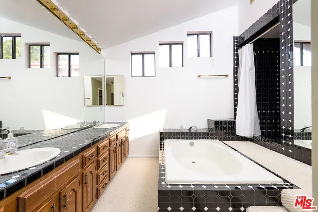 a spacious bathroom with a granite countertop double vanity sink a mirror and a bathtub