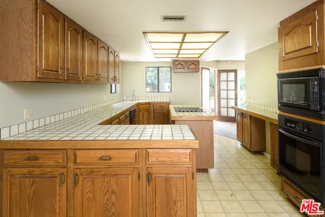 a kitchen with granite countertop a sink a stove cabinets and appliances