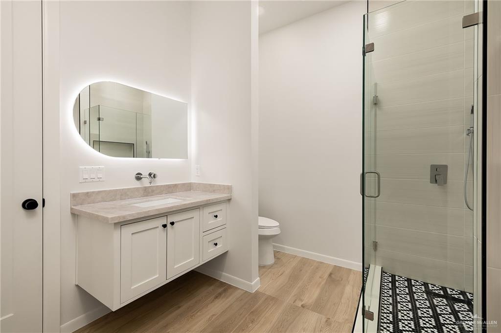 1107 Benjamin Street Mission, TX 78573 - Photo 18 of 19 Floating vanity with integrated sink, stone countertop, and back-lit mirror