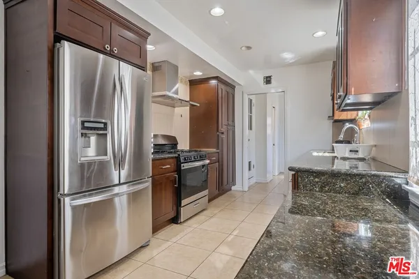 a kitchen with stainless steel appliances granite countertop a refrigerator and a stove