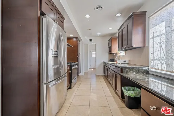 a large kitchen with stainless steel appliances granite countertop a refrigerator and a sink