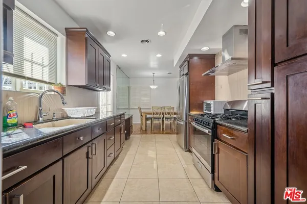 a kitchen with stainless steel appliances granite countertop a sink a stove and a refrigerator