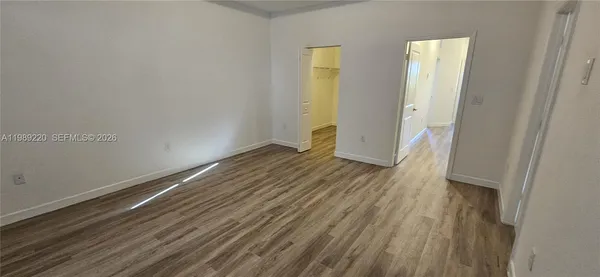 a view of an empty room with wooden floor and a window