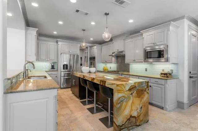 a kitchen with kitchen island granite countertop a sink stove and refrigerator