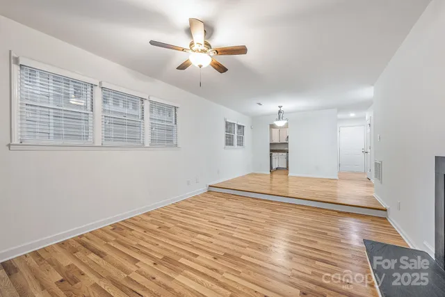 a view of a room with wooden floor and a ceiling fan