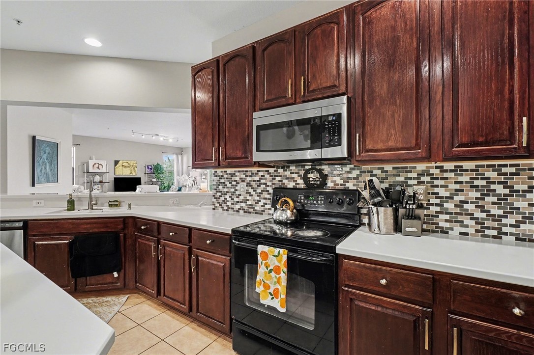 3799 Costa Maya Way, Unit 101 Estero, FL 33928 - Photo 11 of 35 a kitchen with granite countertop stainless steel appliances a stove sink and cabinets