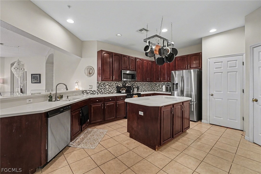 3799 Costa Maya Way, Unit 101 Estero, FL 33928 - Photo 13 of 35 a kitchen with kitchen island granite countertop a sink dishwasher a refrigerator a oven and a refrigerator with wooden cabinets
