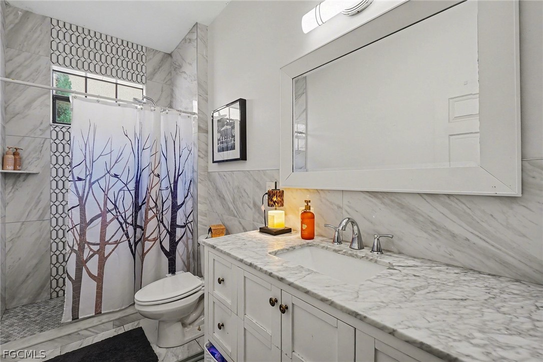 3799 Costa Maya Way, Unit 101 Estero, FL 33928 - Photo 22 of 35 a bathroom with a granite countertop sink and a toilet