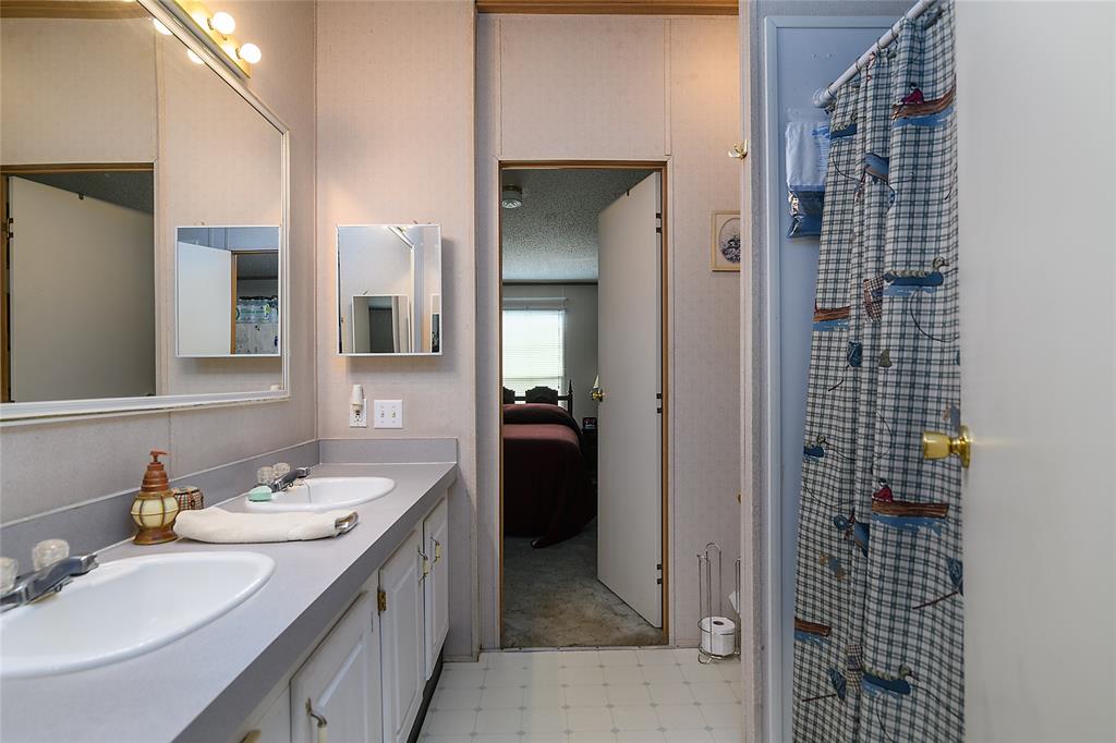 122 Grice Road Ringgold, LA 71068 - Photo 15 of 26 Bathroom featuring a dual vanity with integrated sinks, a wall-mounted mirror, and cabinet storage