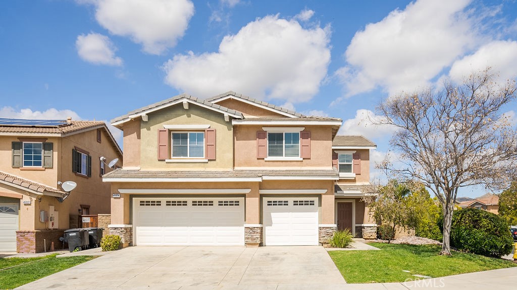 a view of a white house with a large tree and plants