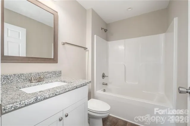 a bathroom with a granite countertop sink a toilet and shower
