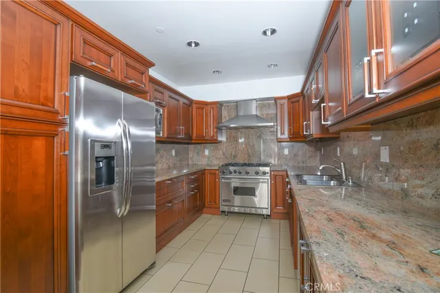 a kitchen with stainless steel appliances granite countertop a sink a stove and a refrigerator
