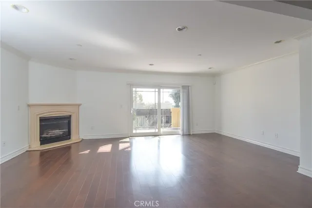 an empty room with wooden floor fireplace and windows