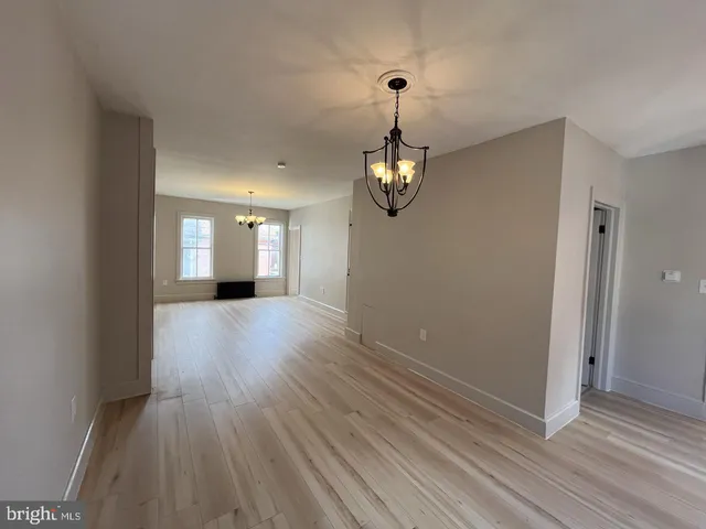 an empty room with wooden floor mirror and windows