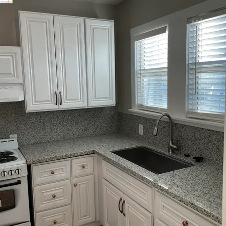 a kitchen with granite countertop white cabinets and sink