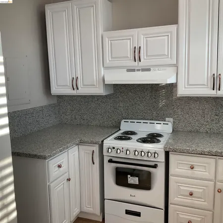 a kitchen with granite countertop white cabinets and white stove