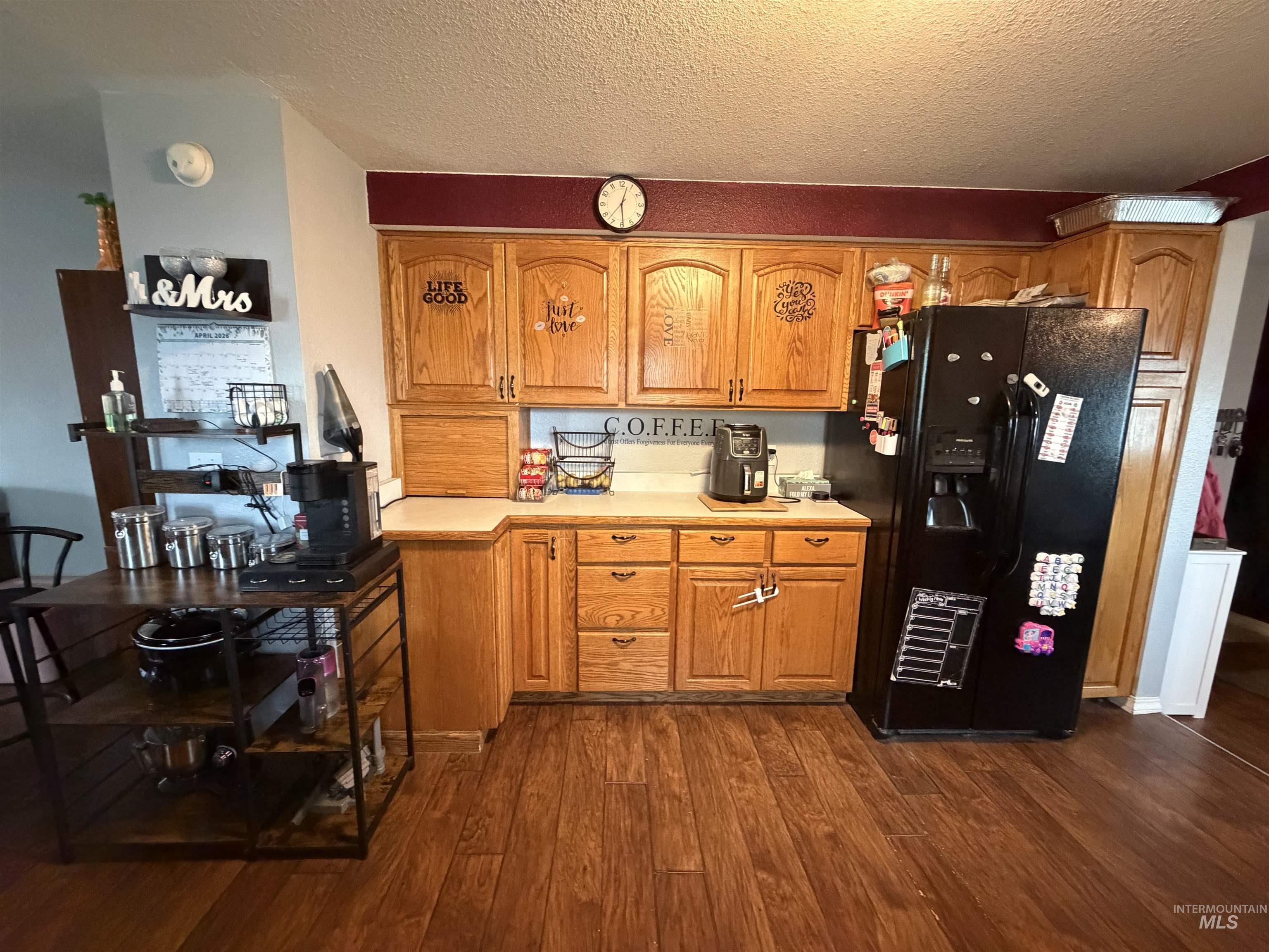 1602 14th Avenue Lewiston, ID 83501 - Photo 17 of 32 Kitchen with light countertops, black fridge with ice dispenser, dark wood-style floors, a textured ceiling, and wood finish cabinets