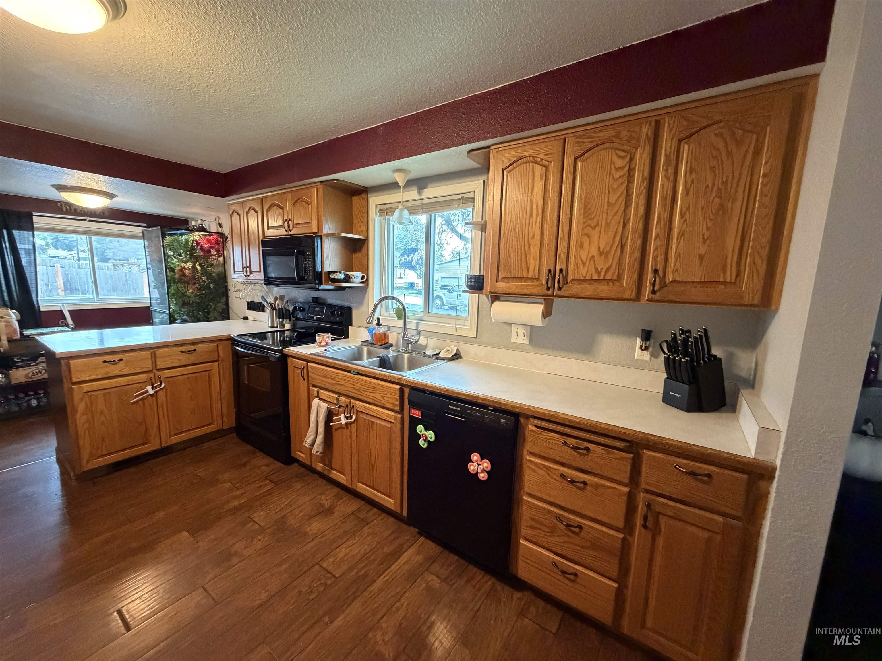 1602 14th Avenue Lewiston, ID 83501 - Photo 18 of 32 Kitchen with light countertops, black appliances, wood finish cabinetry, a textured ceiling, and dark wood finished floors
