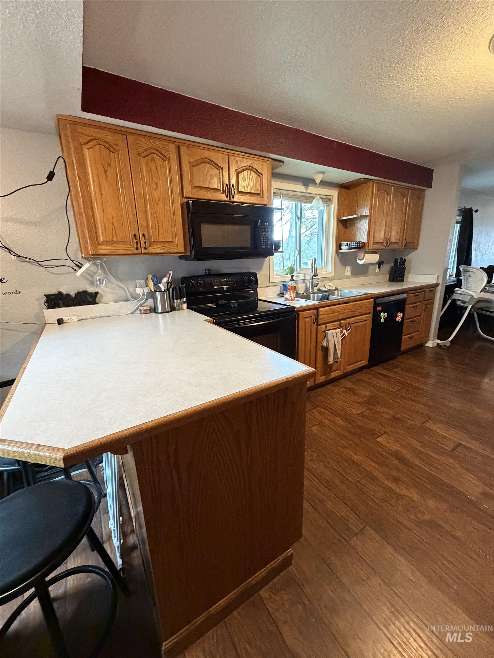 1602 14th Avenue Lewiston, ID 83501 - Photo 19 of 32 Kitchen featuring a textured ceiling, black appliances, light countertops, wood finish cabinets, and dark wood-style floors