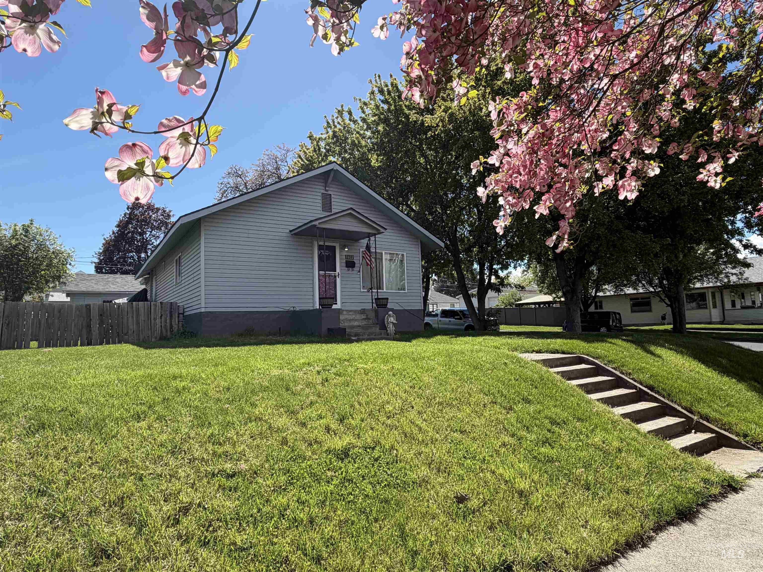 1602 14th Avenue Lewiston, ID 83501 - Photo 5 of 32 Light blue siding on a residential structure, featuring a covered front entry, a sloped front lawn, and concrete steps from the sidewalk