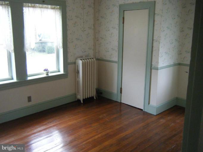 208 West Maple Road Linthicum Heights, MD 21090 - Photo 11 of 19 a view of an empty room with wooden floor and a window