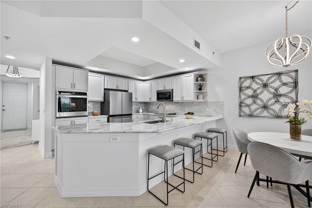 14380 Riva Del Lago Drive, Unit 802 Fort Myers, FL 33907 - Photo 9 of 49 a kitchen with stainless steel appliances kitchen island granite countertop a table chairs microwave and sink