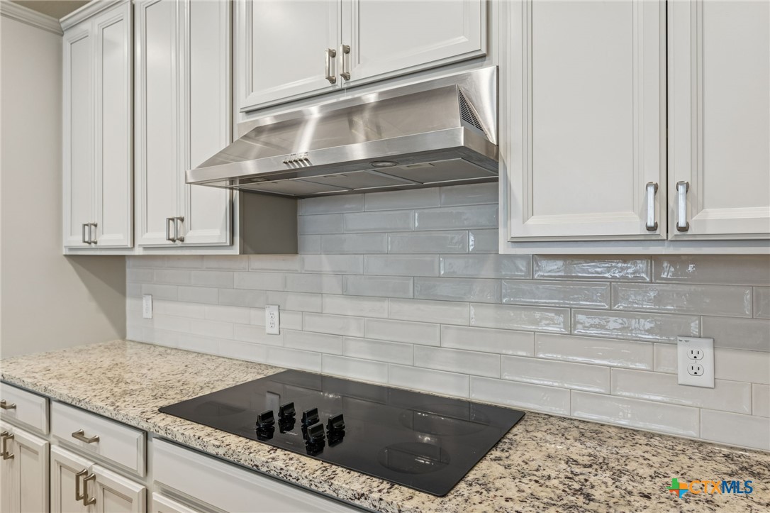 4008 Wild Bloom Road Seguin, TX 78155 - Photo 11 of 40 a kitchen with granite countertop white cabinets and a stove