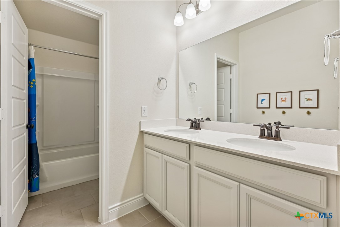 4008 Wild Bloom Road Seguin, TX 78155 - Photo 30 of 40 a bathroom with a double vanity sink a mirror and a shower