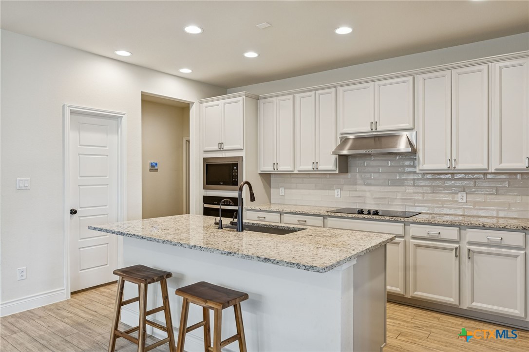 4008 Wild Bloom Road Seguin, TX 78155 - Photo 8 of 40 a kitchen with kitchen island granite countertop a sink a stove a counter space and cabinets