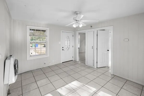 a view of an empty room with window and chandelier fan