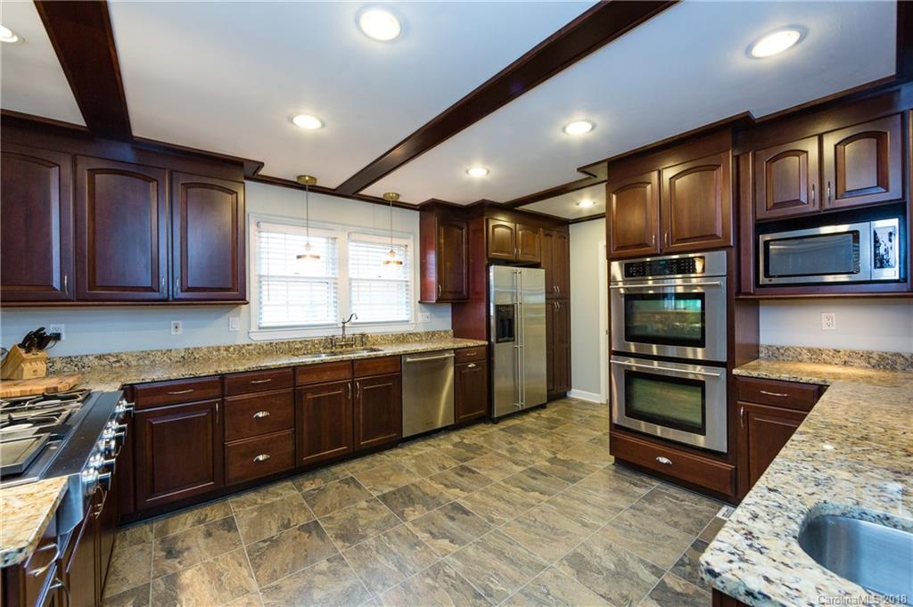 4615 Walker Road Charlotte, NC 28211 - Photo 11 of 28 a kitchen with stainless steel appliances granite countertop wooden cabinets a stove top oven a sink and dishwasher
