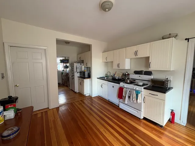 a kitchen with a refrigerator and wooden floor